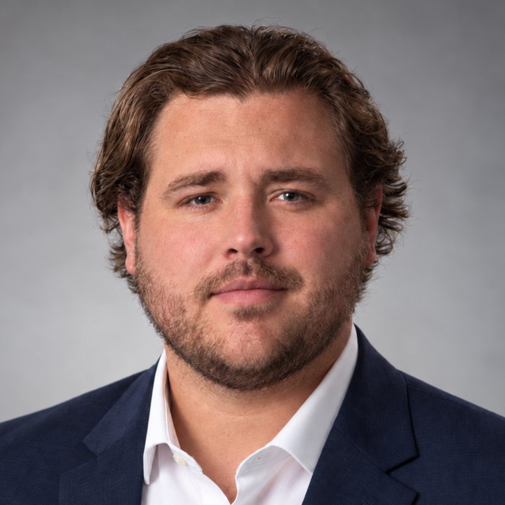 Headshot of Coach Tanner Rose in a navy blazer and white shirt